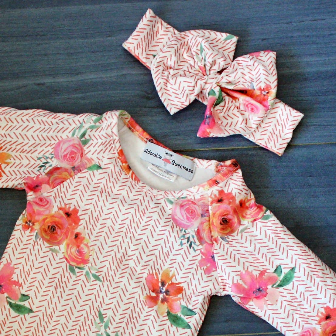 Floral-patterned baby romper with matching headband on a blue surface